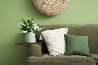 Oturma odasının içinde kanepe ve vazoyla çiçek açmış yasemin çiçekleri, yakın plan.