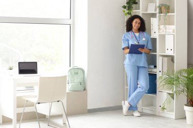 Afro-Amerikan tıp öğrencisi. Ofiste panoya yazı yazıyor.