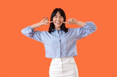 Turuncu arka planda güzel gülüşü olan genç bir kadın.