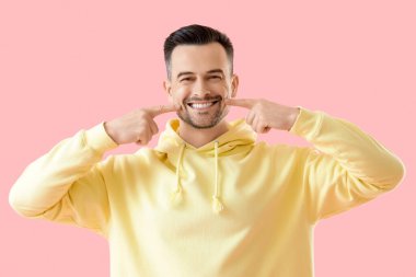 Pembe arka planda güzel gülüşü olan genç adam.