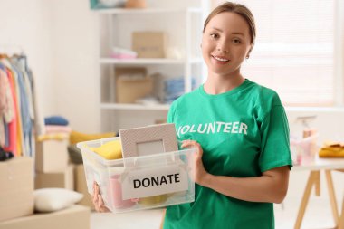 Gönüllü bir kadın konteynırın içinde bağış amaçlı eşyalar taşıyor.