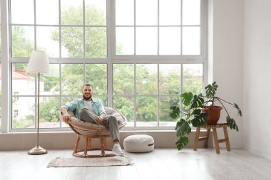 Evdeki kozada oturan yakışıklı adam.