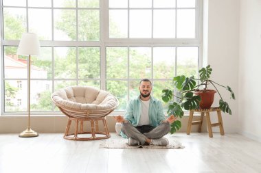 Evdeki kozanın yanında meditasyon yapan yakışıklı bir adam.