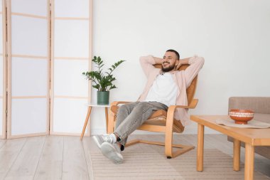 Evdeki kahverengi koltukta dinlenen yakışıklı adam.