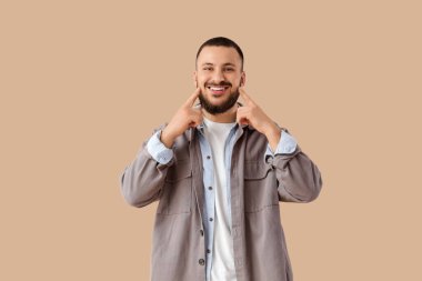 Bej arka planda güzel gülüşü olan genç adam.