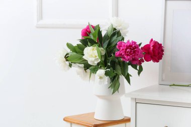 Işık odasında, masasında güzel şakayıklar olan vazo, yakın plan.