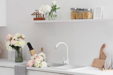 Lavabosu, rafı ve güzel şakayıkları olan şık bir mutfak.