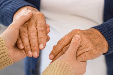 Büyükannesi evde el ele tutuşan bir kadın, yakın çekim. Bakım kavramı