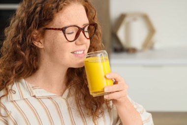 Mutfakta zerdeçal içkisi olan genç kızıl saçlı kadın, yakın plan.