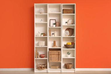 Turuncu duvarın yanında şık dekorlu raflar.