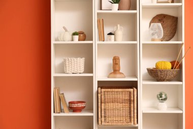 Turuncu duvarın yanında şık dekorlu raflar.