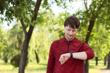 Erkek koşucu parkta akıllı saati kontrol ediyor
