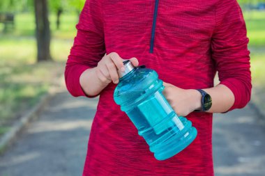 Parkta su şişesi olan erkek koşucu, yakın plan.
