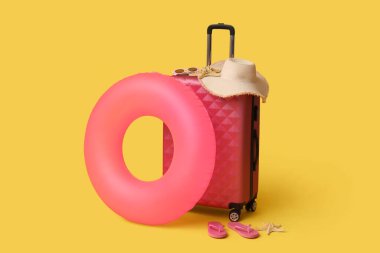 Çanta, şişirilebilir yüzük ve sarı arka planda plaj aksesuarları.