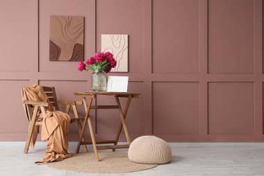 Odanın içinde şık tablolar, sandalye ve masa var.