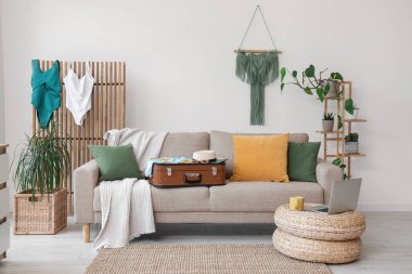 Oturma odasının içinde kanepe, katlanan mayolar ve bitkiler.