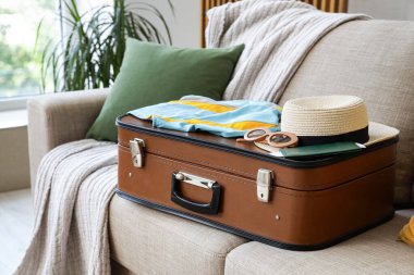 Oturma odasındaki kanepede plaj aksesuarları olan bavul, yakın plan.