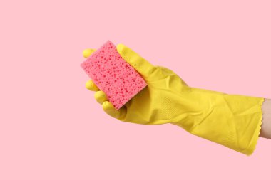 Pembe arka planı temizlemek için kauçuk eldiven tutuyordu.