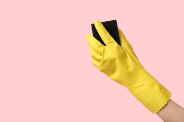 Pembe arka planı temizlemek için kauçuk eldiven tutuyordu.