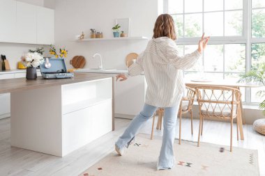 Güzel genç bayan mutfakta dans ediyor.