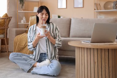 Evde buzlu latte içen genç bir kadın.