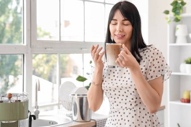 Mutfakta bir bardak buzlu latte ile genç bir kadın.