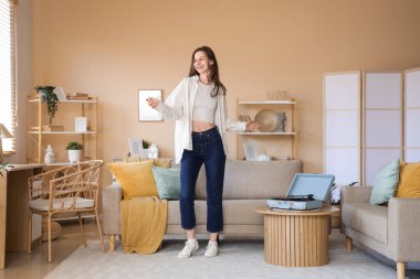 Evde pikabı olan genç bir kadın dans ediyor.