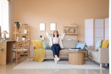 Evdeki kanepede dinlenen pikabı olan genç bir kadın.