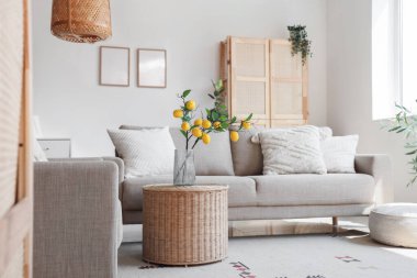 Oturma odasının içinde bej renkli kanepe ve beyaz duvarın yanındaki masa.