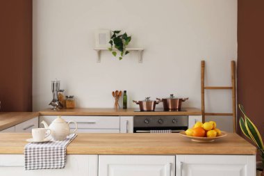 Şık bir mutfak tezgahında taze meyve ve çaydanlık.