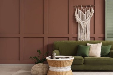 Yeşil kanepeli, çiçekli ve kahve masalı şık bir oturma odası.