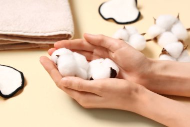 Sarı arka planda pamuk çiçekli kadın eller, yakın plan.