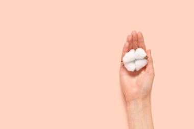 Pembe arka planda pamuk çiçekli kadın eli, yakın plan.