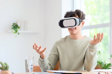 Ofisteki masada VR gözlük takan genç adam.