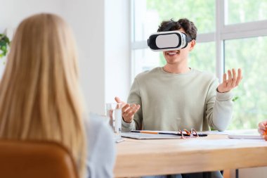 Ofisteki masada VR gözlük takan genç adam.