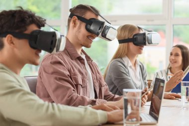 Ofisteki masada VR gözlüğü kullanan genç meslektaşlar.