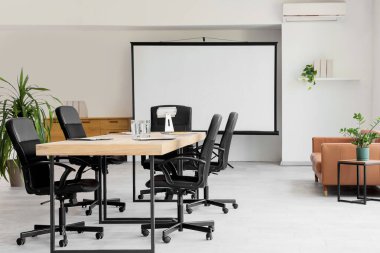 Masa, bitki ve projektör ekranlı konferans salonunun içi