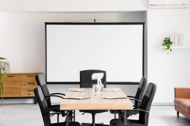 Masa ve projektör ekranlı konferans salonunun içi