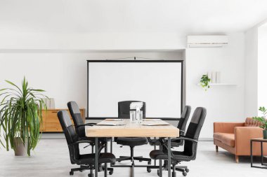 Masa, bitki ve projektör ekranlı konferans salonunun içi