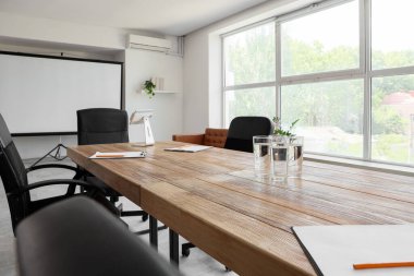 Konferans salonunda yapılacak iş toplantısı için hazırlanmış su ve panolarla dolu bir masa.