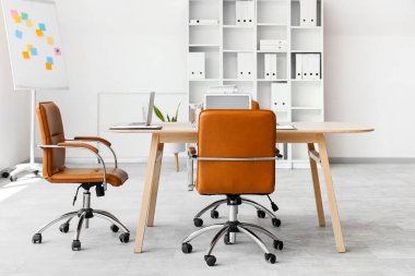 Masası, tablosu ve raf ünitesi olan konferans salonunun içi.