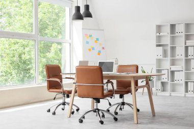 Masası, tablosu ve raf ünitesi olan konferans salonunun içi.