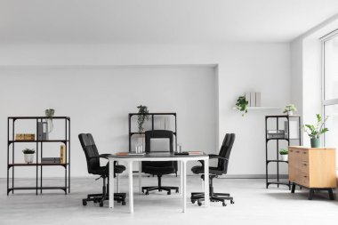 Konferans salonunun içinde masa, bitki ve raf üniteleri var.