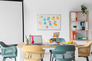 Masa, tahta ve raf ünitesi olan konferans salonunun içi.