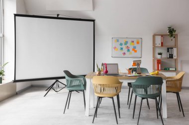 Masa, projektör ekranı ve beyaz tahtası olan konferans salonunun içi