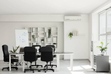 Masası, tablosu ve raf ünitesi olan konferans salonunun içi.