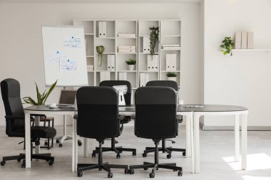 Masası, tablosu ve raf ünitesi olan konferans salonunun içi.