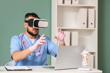 Klinikteki masada VR gözlüğü kullanan bir erkek doktor.