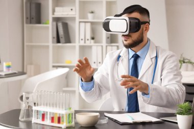 Ofisteki masada VR gözlüğü kullanan bir erkek doktor.