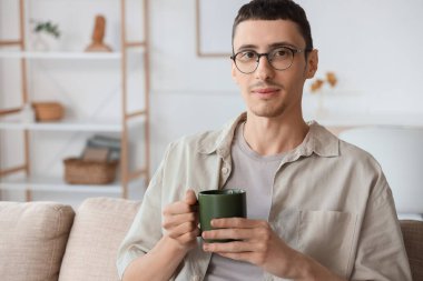 Gözlüklü genç adam evde bir fincan çayla